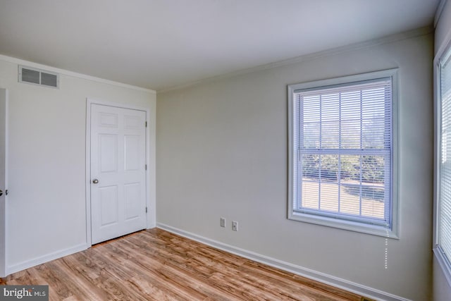 spare room featuring ornamental molding and light wood-type flooring