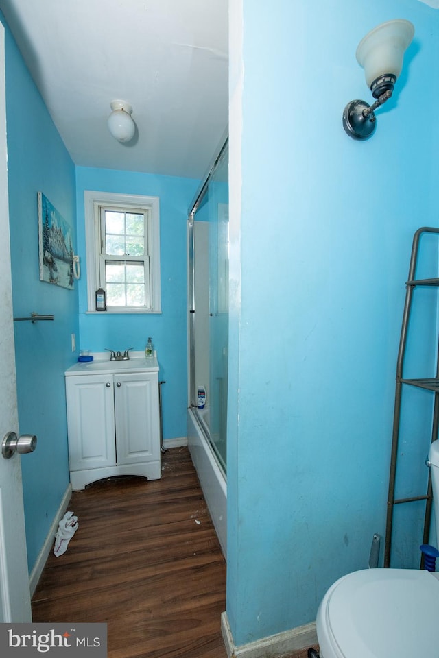 full bathroom with vanity, toilet, wood-type flooring, and shower / bath combination with glass door