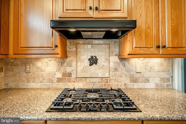 kitchen with ventilation hood, light stone countertops, black gas stovetop, and backsplash