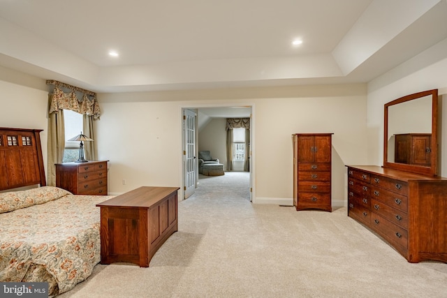 bedroom with multiple windows, a raised ceiling, light carpet, and french doors