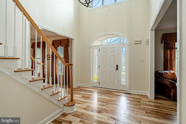 entrance foyer with a towering ceiling and light wood-type flooring