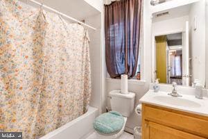 full bathroom featuring vanity, shower / tub combo with curtain, and toilet