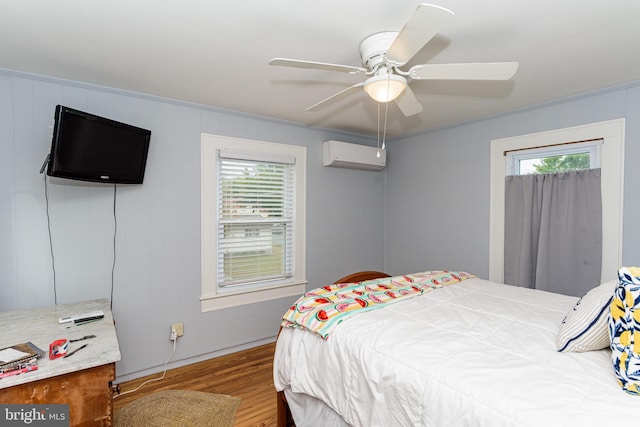 bedroom featuring a wall unit AC, multiple windows, light wood-type flooring, and ceiling fan