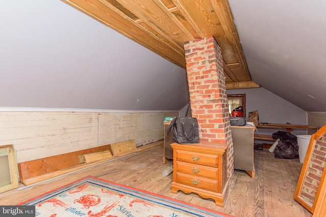 interior space featuring light hardwood / wood-style flooring, wooden walls, and vaulted ceiling