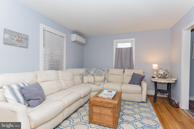 living room with a wall mounted AC and light hardwood / wood-style flooring