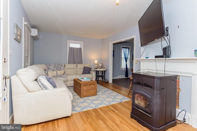 living room featuring an AC wall unit, a wood stove, and light hardwood / wood-style flooring