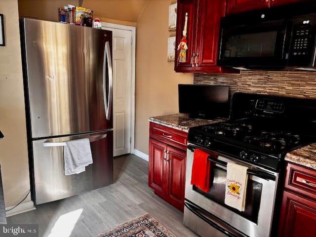 kitchen featuring decorative backsplash, light stone countertops, stainless steel appliances, and light wood-type flooring