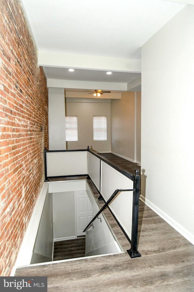 stairway featuring brick wall and hardwood / wood-style floors