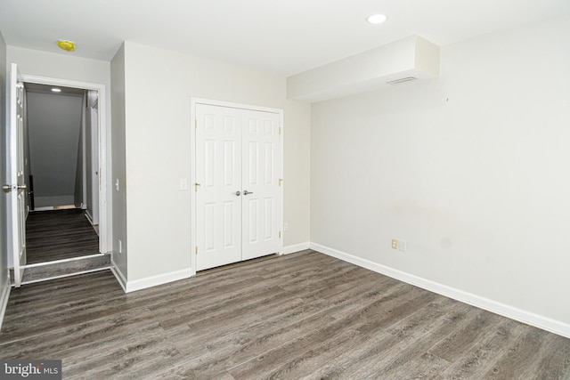 unfurnished bedroom with a closet and dark hardwood / wood-style flooring