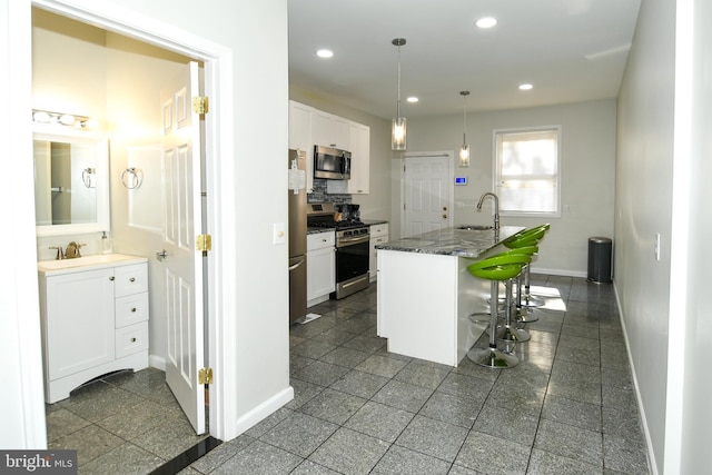 kitchen featuring sink, a kitchen bar, an island with sink, stainless steel appliances, and white cabinets