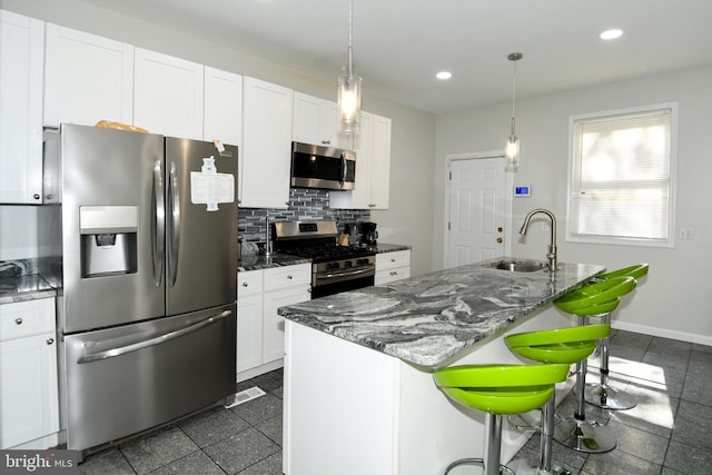 kitchen with a breakfast bar, white cabinetry, a kitchen island with sink, sink, and stainless steel appliances