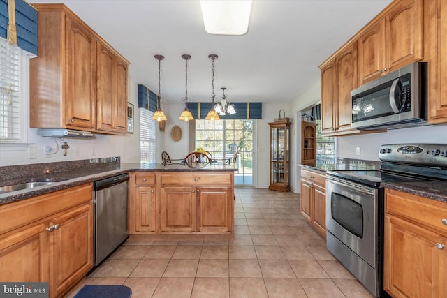 kitchen with appliances with stainless steel finishes, kitchen peninsula, hanging light fixtures, and light tile patterned floors