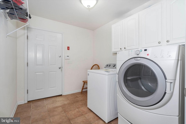 clothes washing area featuring light tile patterned flooring, washing machine and clothes dryer, and cabinets