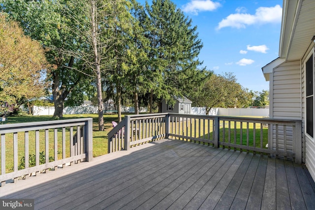 wooden deck featuring a storage shed and a lawn