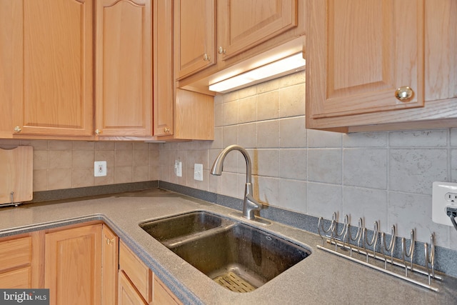 kitchen featuring light brown cabinetry, decorative backsplash, and sink