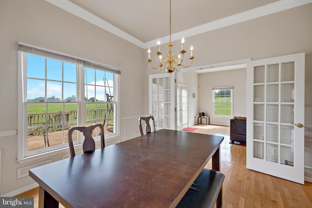 dining space featuring ornamental molding, french doors, a notable chandelier, and light hardwood / wood-style floors