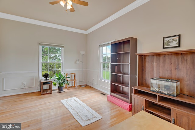 sitting room with light hardwood / wood-style flooring, ornamental molding, and a healthy amount of sunlight