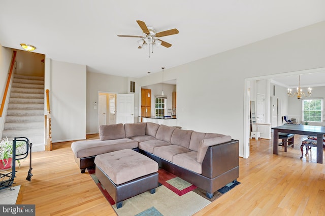 living room with ceiling fan with notable chandelier and light wood-type flooring