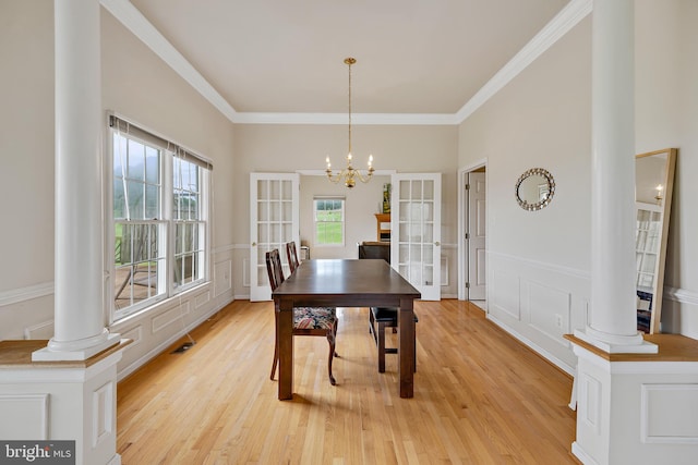 dining space with a notable chandelier, decorative columns, light hardwood / wood-style flooring, and ornamental molding