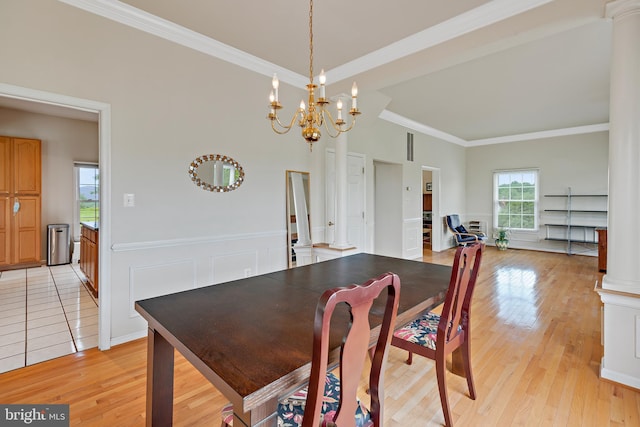 dining space with crown molding, light wood-type flooring, and decorative columns