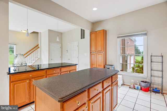 kitchen with dark stone counters, light tile patterned flooring, a center island, and pendant lighting