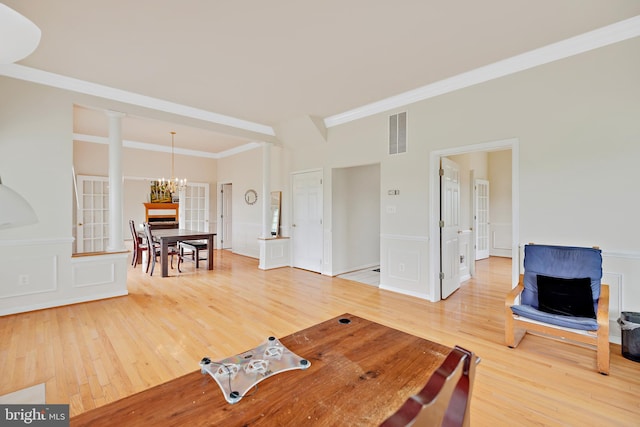 living room featuring a chandelier, crown molding, ornate columns, and wood-type flooring