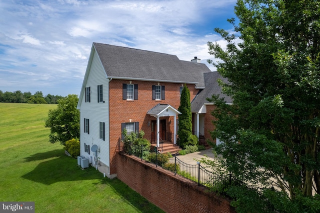 view of front facade with cooling unit and a front lawn