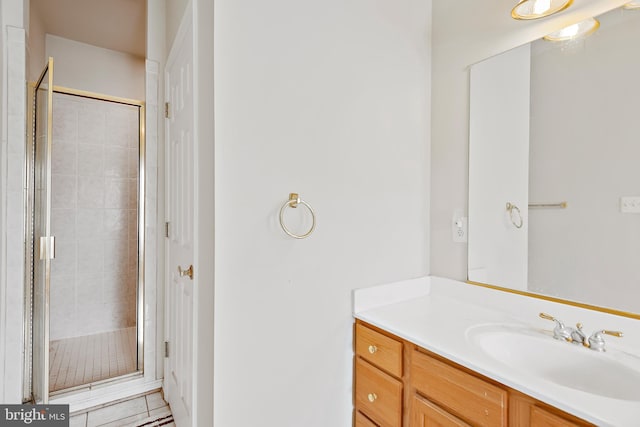 bathroom featuring a shower with door, vanity, and tile patterned floors