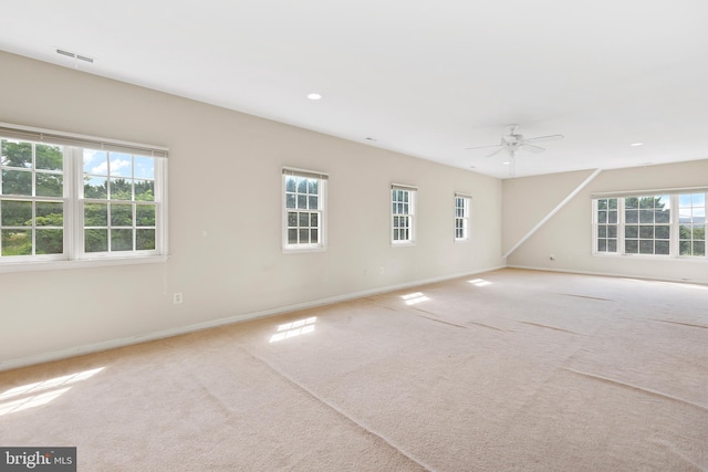 carpeted spare room with a wealth of natural light and ceiling fan