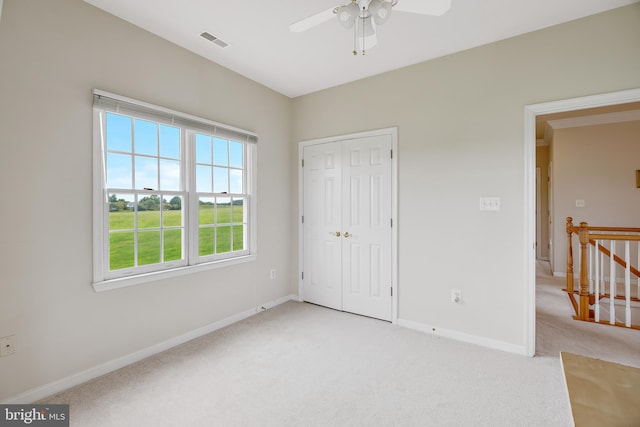 unfurnished bedroom with a closet, light colored carpet, and ceiling fan