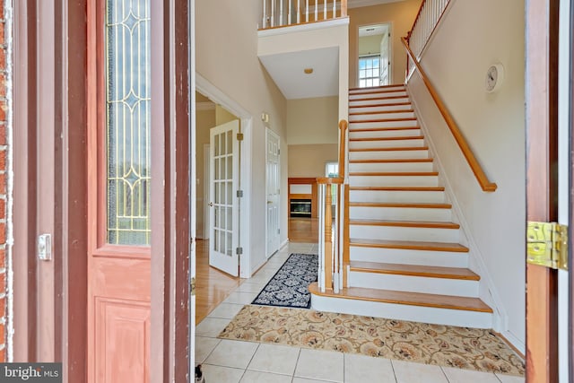 entryway with a wealth of natural light, light tile patterned flooring, and high vaulted ceiling