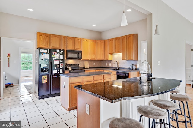 kitchen featuring tasteful backsplash, black appliances, sink, decorative light fixtures, and a center island