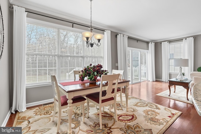 dining room with a healthy amount of sunlight, a notable chandelier, and hardwood / wood-style flooring