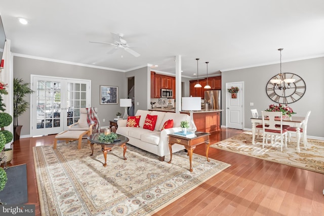 living room featuring french doors, sink, dark wood-type flooring, crown molding, and ceiling fan with notable chandelier