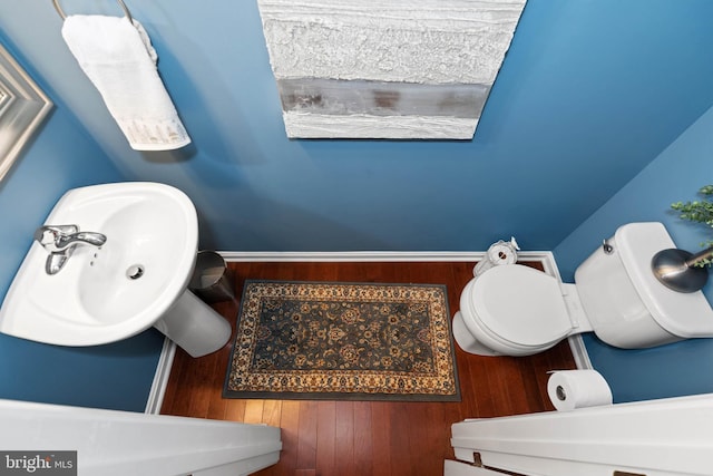 bathroom featuring wood-type flooring, toilet, and sink