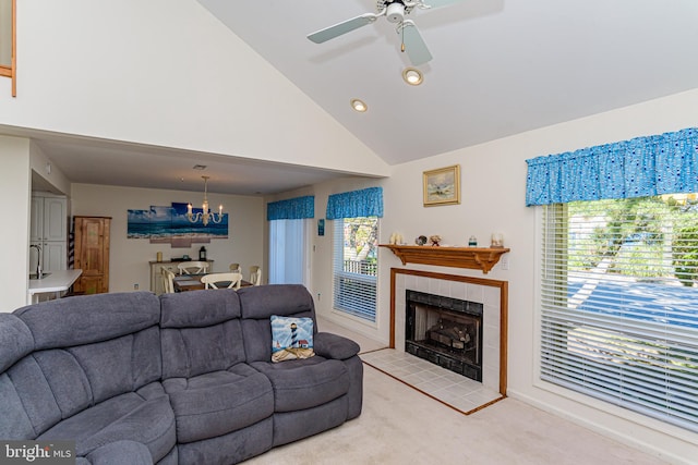 living room with a tiled fireplace, light colored carpet, high vaulted ceiling, and ceiling fan