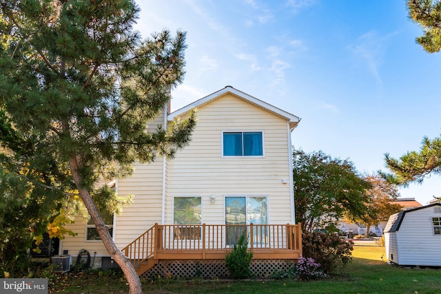 back of house featuring central AC, a deck, and a lawn