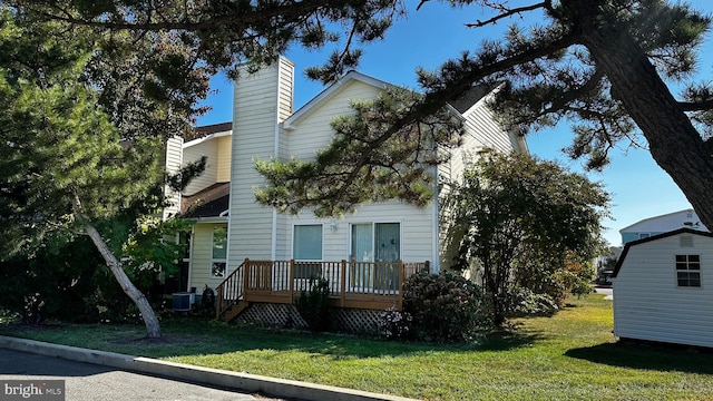 view of front of property with a deck, a front lawn, and central AC unit