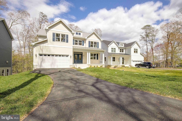 view of front of home featuring covered porch, a garage, and a front lawn