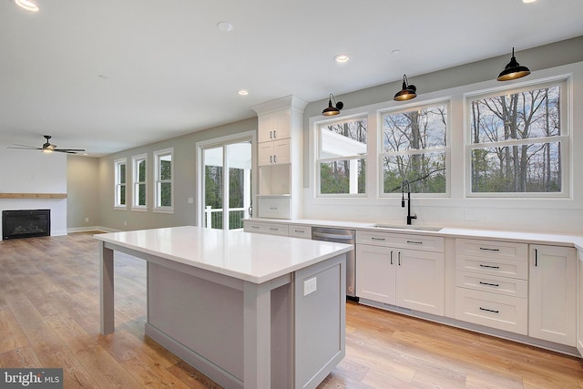 127 Shore Rd, Arnold, MD 21012 - kitchen featuring stainless steel dishwasher, a sink, a ceiling fan, a glass covered fireplace, and a center island