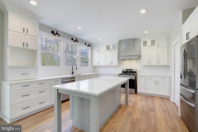 kitchen with white cabinets, custom range hood, light wood-type flooring, and stainless steel appliances