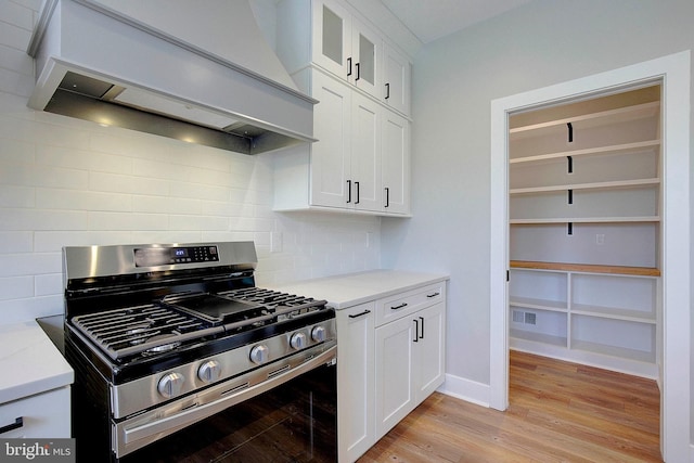 127 Shore Rd, Arnold, MD 21012 - kitchen with stainless steel gas range, custom exhaust hood, light wood-style floors, tasteful backsplash, and glass insert cabinets