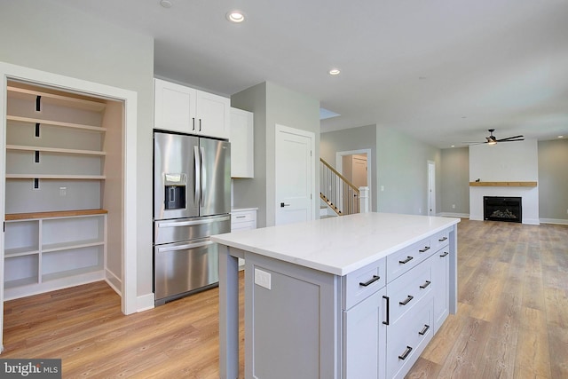 kitchen featuring ceiling fan, a center island, stainless steel fridge with ice dispenser, light hardwood / wood-style floors, and white cabinets