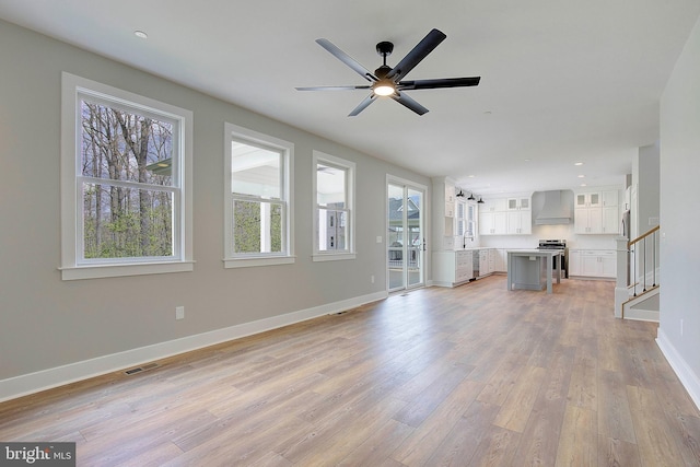 unfurnished living room featuring light hardwood / wood-style floors, ceiling fan, and sink