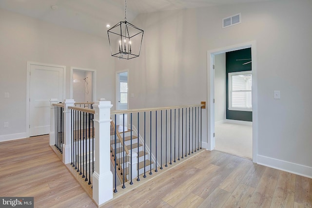 hall with an inviting chandelier, light hardwood / wood-style floors, and high vaulted ceiling