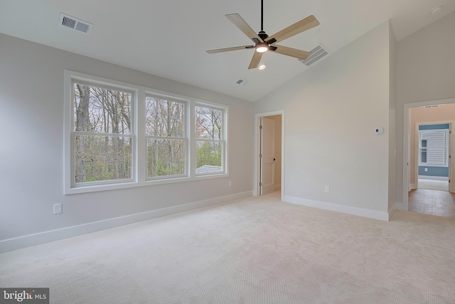 empty room featuring ceiling fan, light colored carpet, and a wealth of natural light