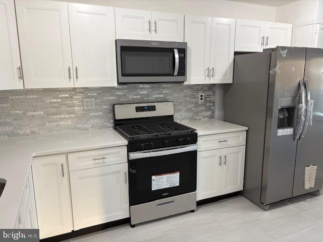 kitchen with white cabinets, stainless steel appliances, and tasteful backsplash