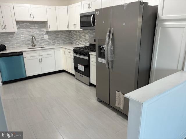 kitchen with appliances with stainless steel finishes, white cabinets, sink, and backsplash