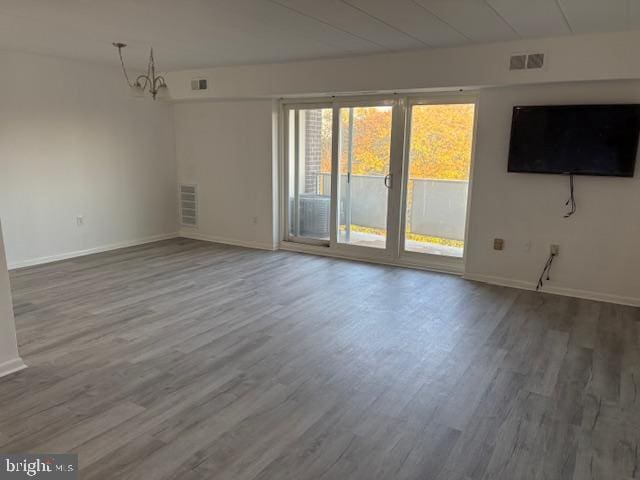 unfurnished room with an inviting chandelier and hardwood / wood-style floors