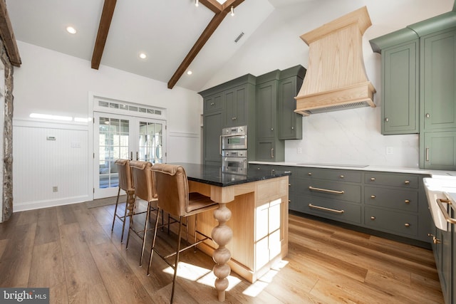 kitchen featuring vaulted ceiling with beams, hardwood / wood-style flooring, a center island, and a kitchen breakfast bar